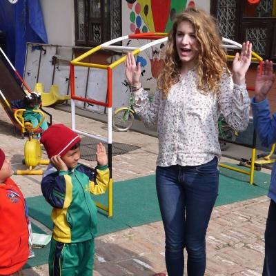 A group of teenage community volunteers working in Nepal, play games with children outside on the playground. Teenage volunteers doing work with children in Nepal, do an activity with children on the playground.